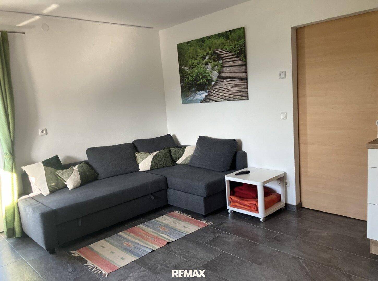 Gemütlicher Wohnbereich mit Ecksofa, Teppich und modernem Wandbild.