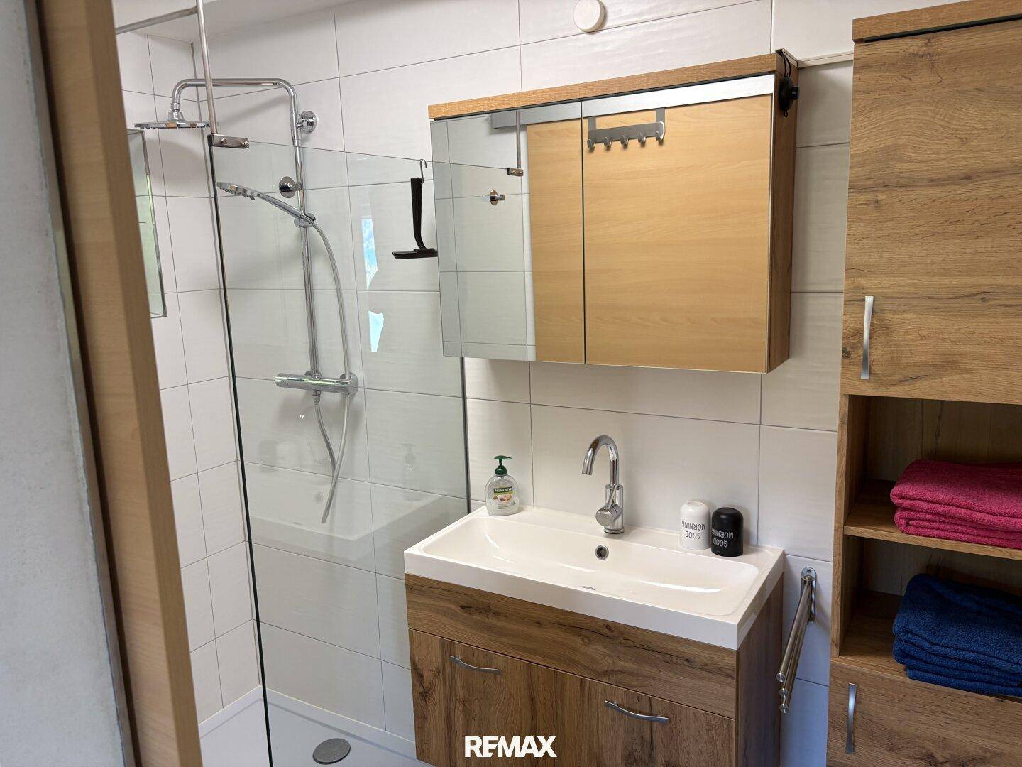 Modernes Badezimmer mit Duschkabine, Waschtisch und Spiegelschrank.