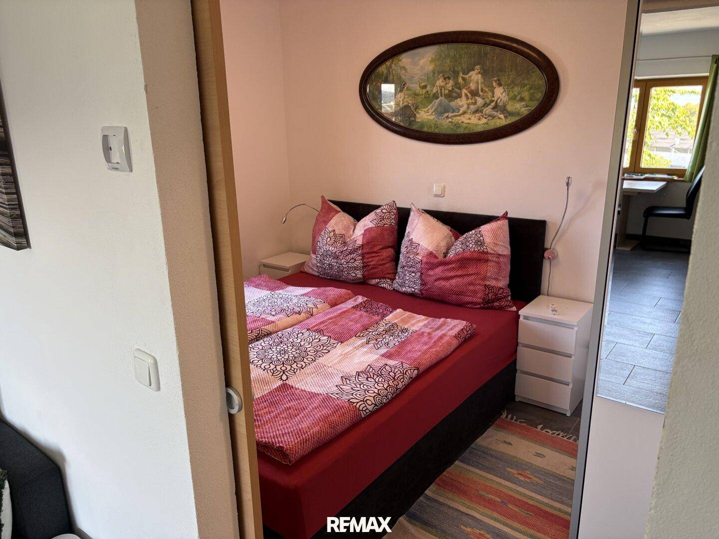 Schlafzimmer mit Doppelbett und Blick in einen angrenzenden Raum.