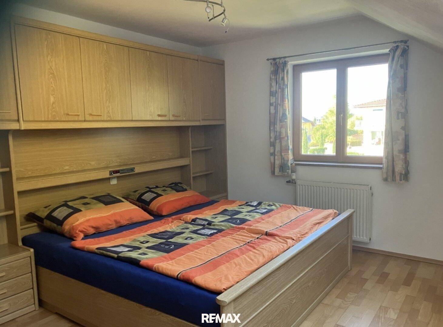 Schlafzimmer mit Doppelbett, Einbauschränken und Fenster mit Blick nach draußen.