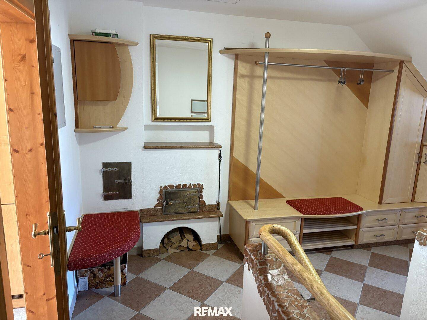 Eingangsbereich mit traditionellem Kachelofen, Garderobe und gemustertem Fliesenboden.