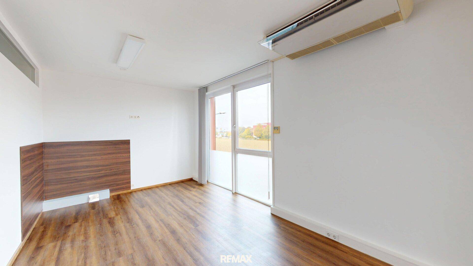 Büroraum mit Klimaanlage, Holzoptikboden und großen Fenstern für angenehmes Raumklima.