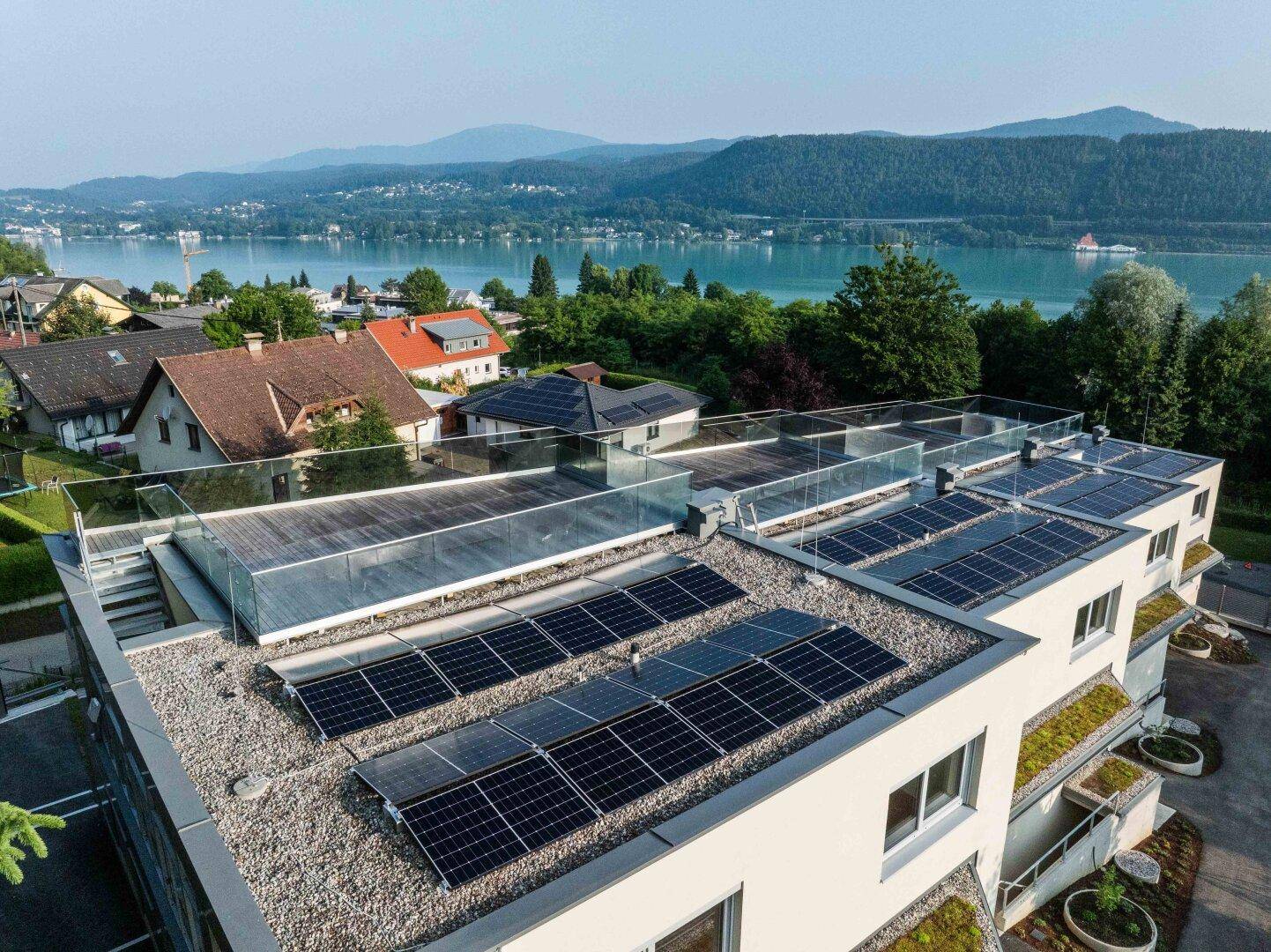 Dachterrassen mit Solaranlagen und Glasgeländern bieten einen weiten Blick auf den See.