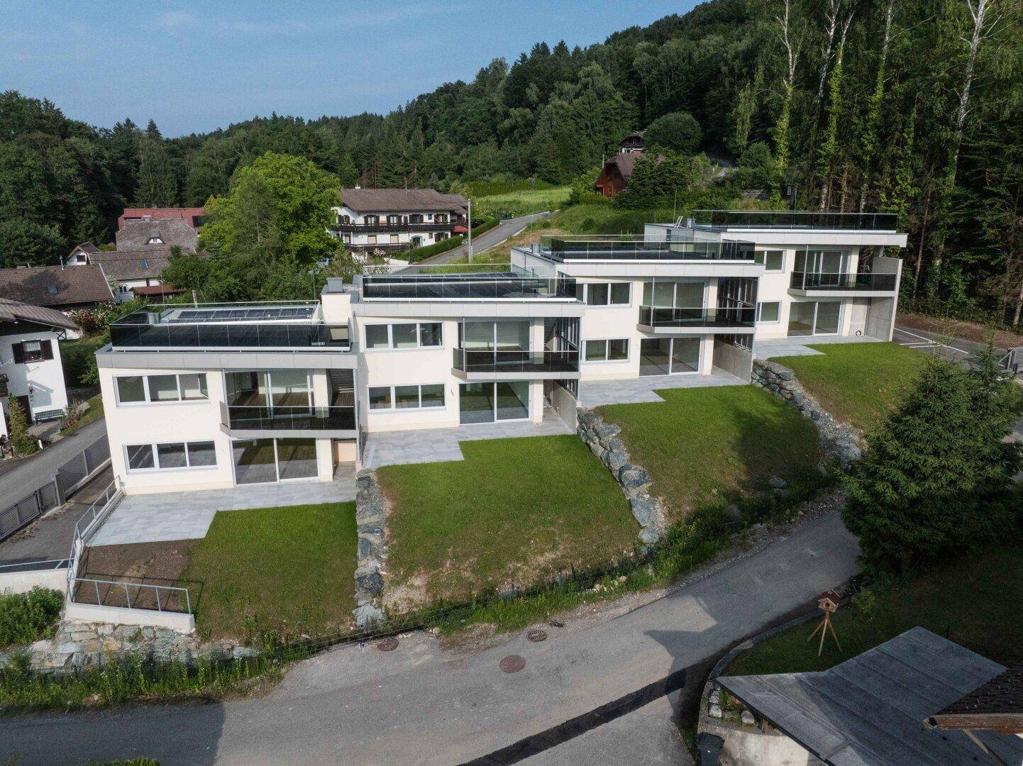 Moderne Wohnanlage mit gestuften Gärten und Terrassen, eingebettet in die Waldlandschaft.