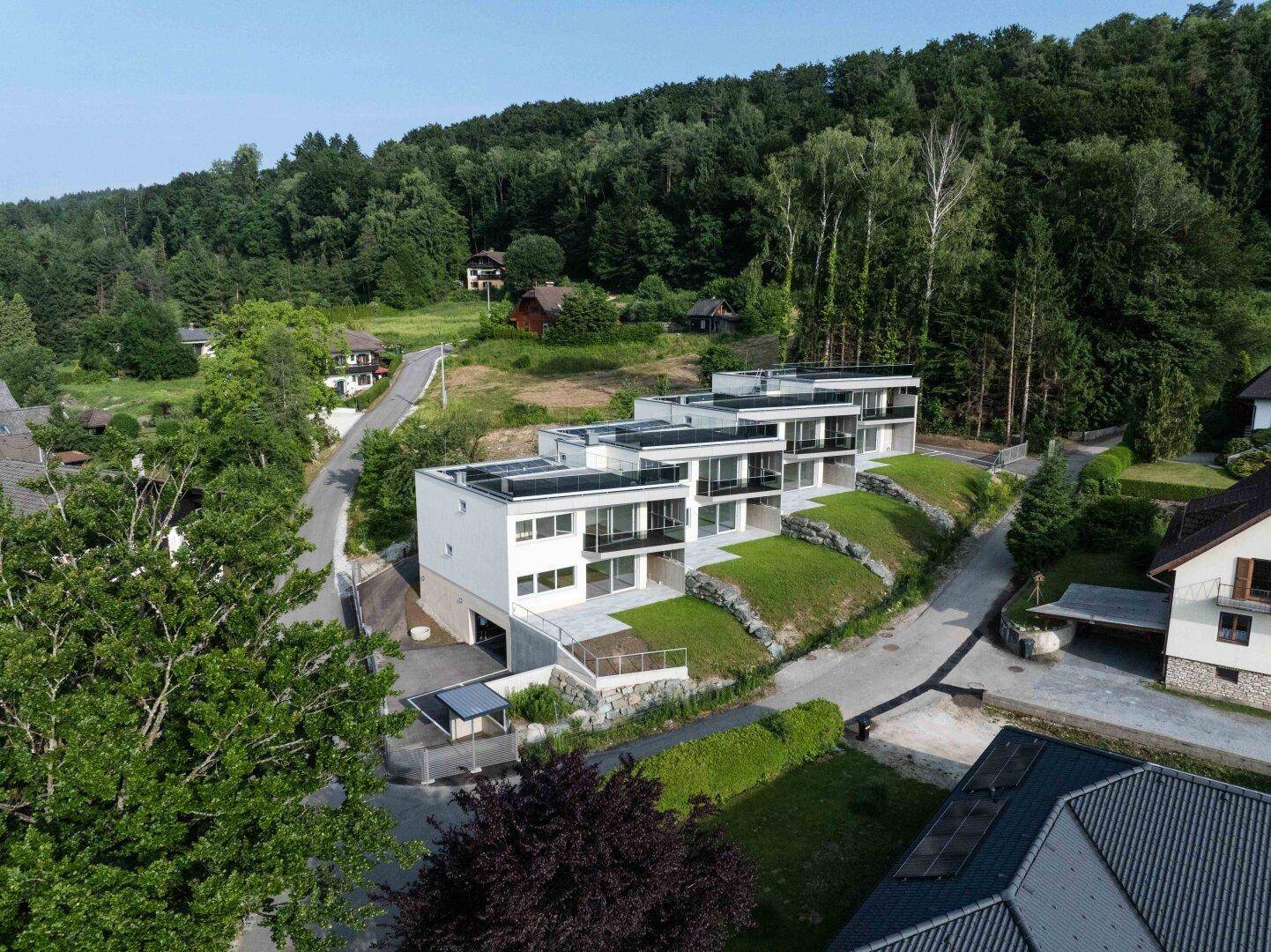 Luftaufnahme der modernen Terrassenhäuser mit umliegenden Straßen und viel Grün.