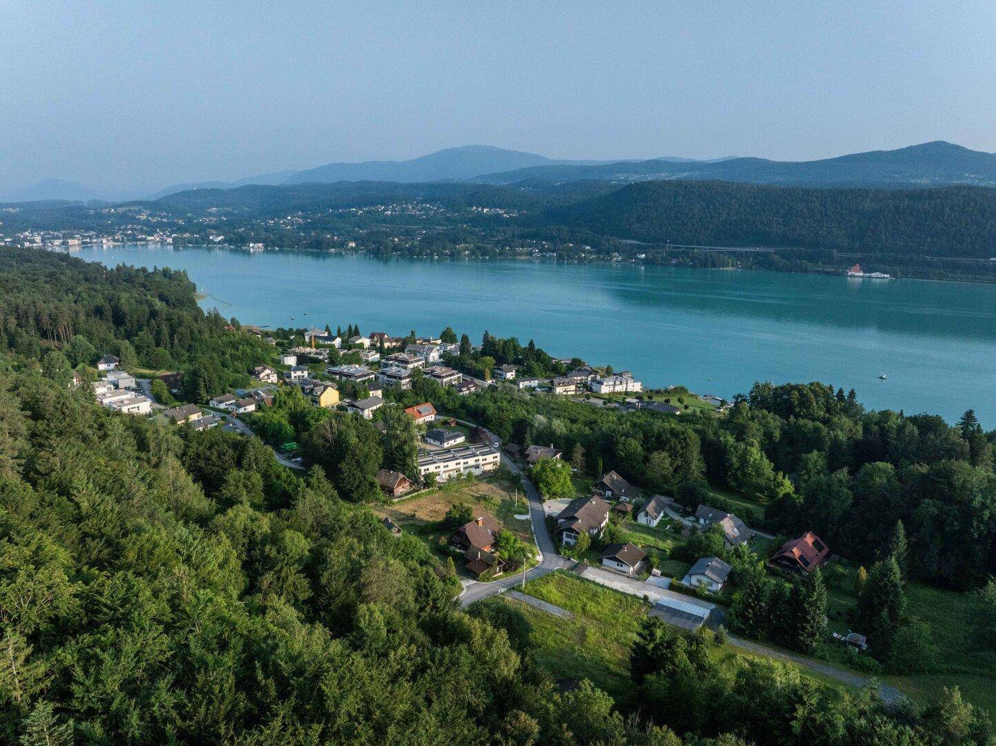 Panoramablick auf den See, die bewaldeten Hügel und die verstreuten Häuser in der Landschaft.