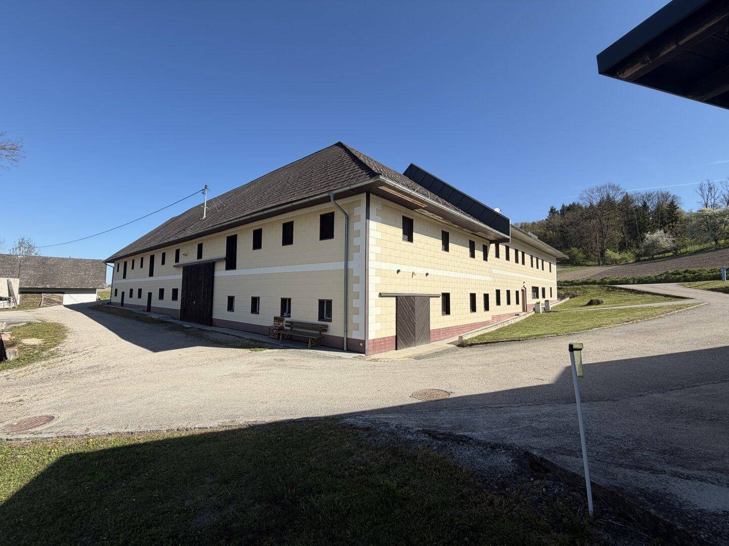 Weitläufiges Anwesen mit großem Gebäude und ländlicher Umgebung unter blauem Himmel.