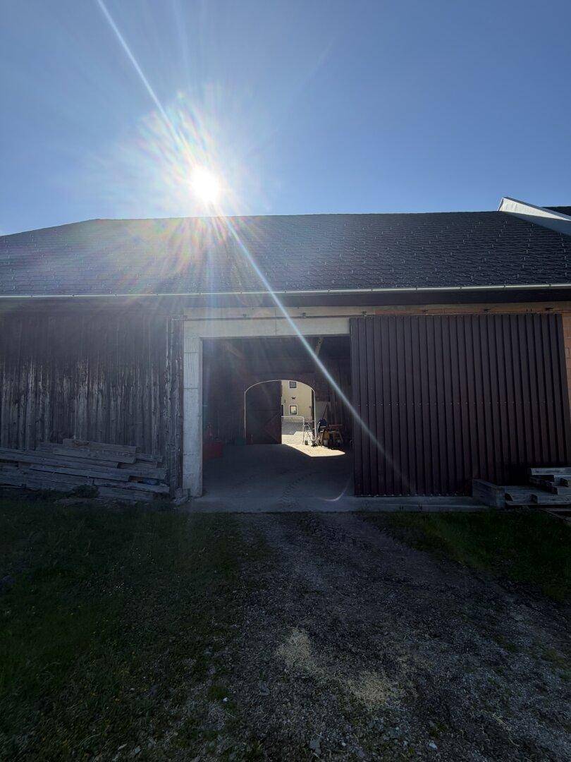 Großer Torbogen führt in einen dunklen Innenbereich, möglicherweise eine Scheune oder Garage.