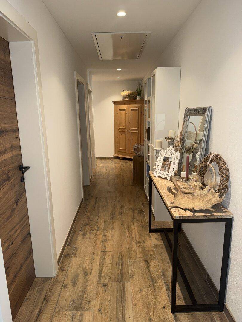 Heller Flur mit Holzboden, dekorativer Konsole und traditionellem Holzschrank.