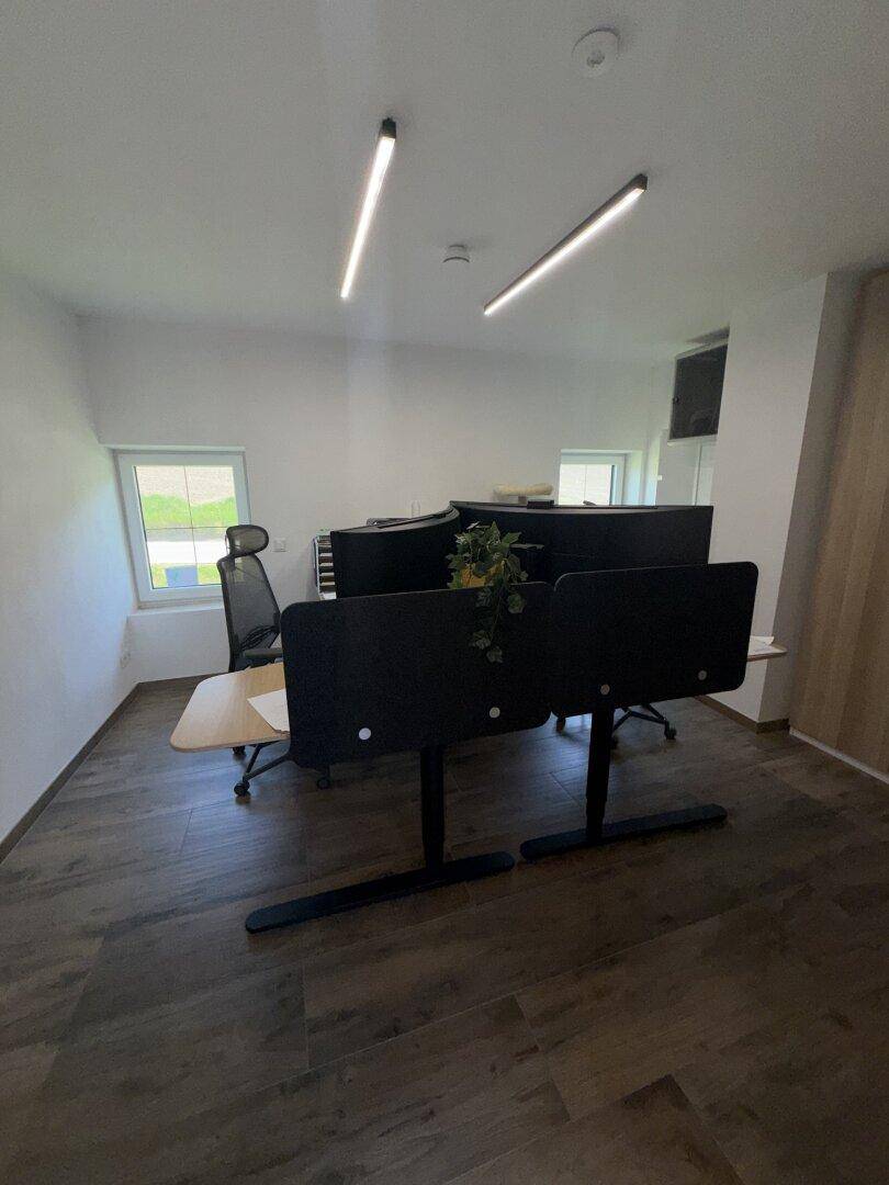 Helles Büro mit mehreren Arbeitsplätzen, modernen Leuchten und Holzboden.