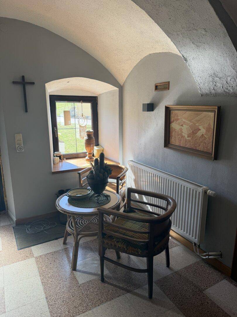 Gemütlicher Eingangsbereich mit Gewölbedecke, kleinem Fenster und traditionellen Möbeln.