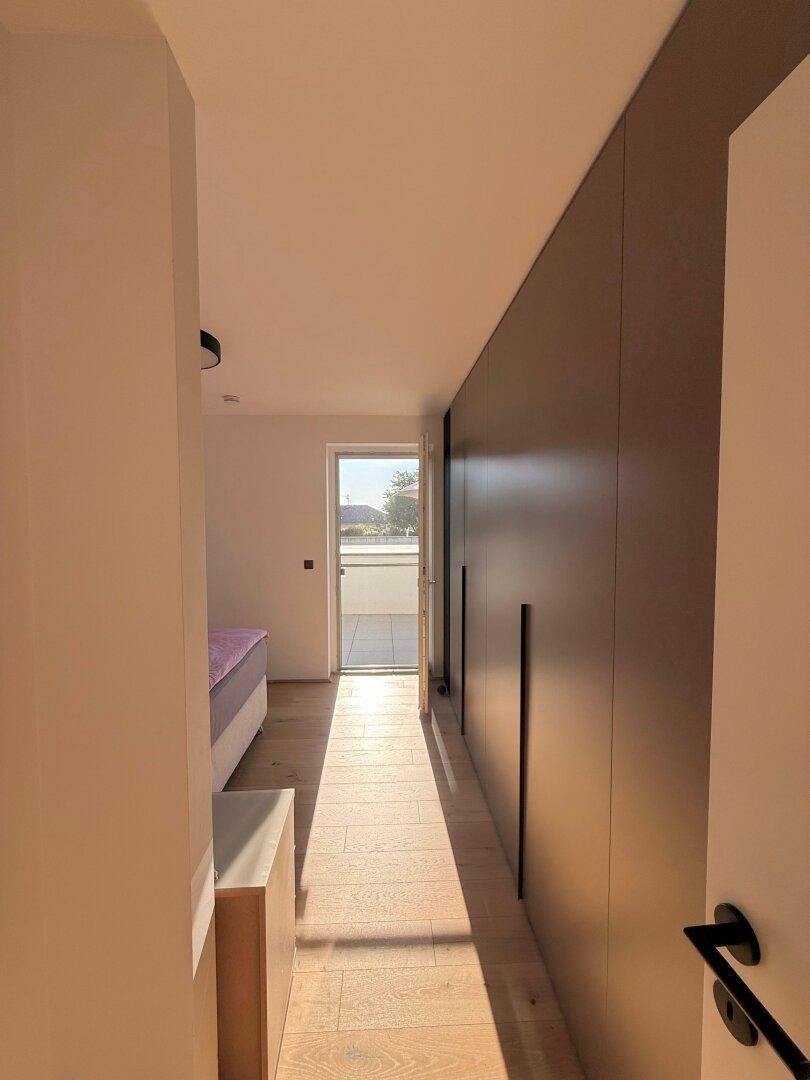 Heller Flur mit Einbauschränken und Zugang zu einem Schlafzimmer sowie einem Außenbereich.