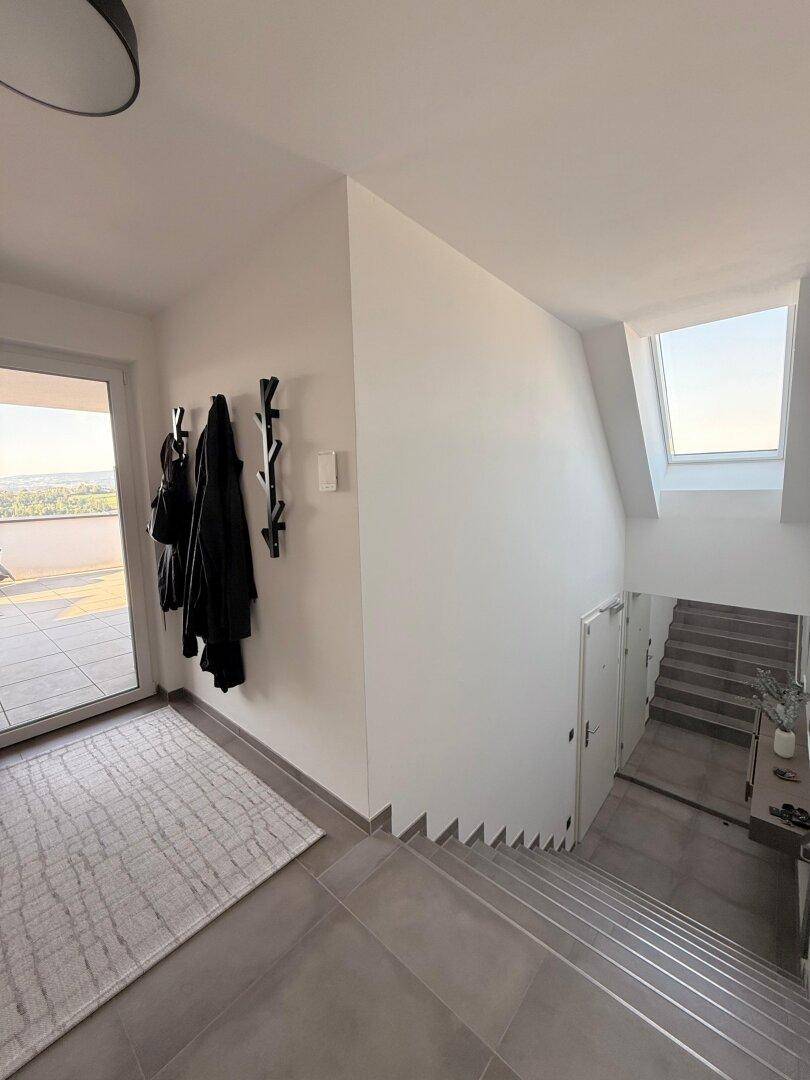 Geräumiger Flur mit Treppenabgang, Garderobe und einem Dachfenster für natürliches Licht.