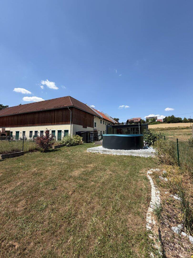 Weitläufiger Gartenbereich mit Pool und Blick auf das Hauptgebäude und die Landschaft.
