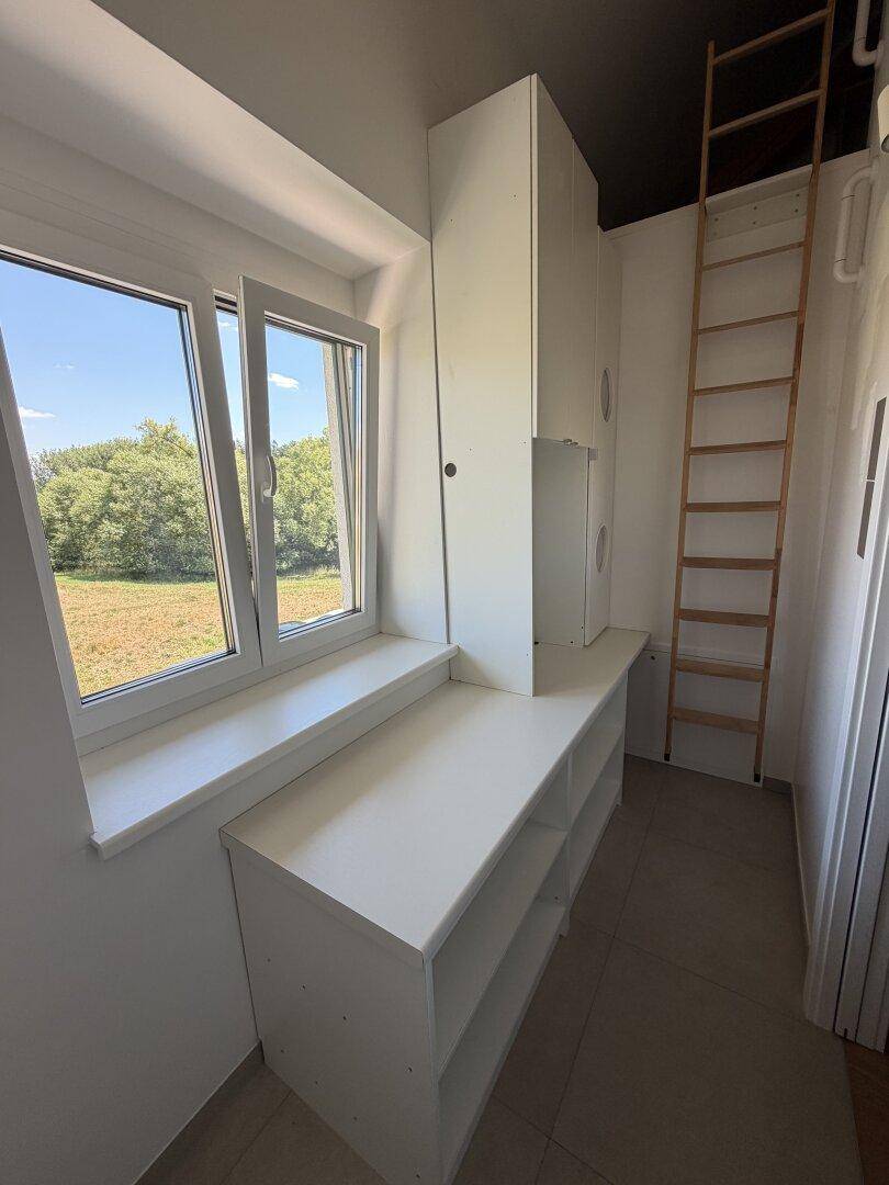 Kleiner Raum mit Fenster, Regalen und Leiter, ideal als Abstell- oder Hauswirtschaftsraum.
