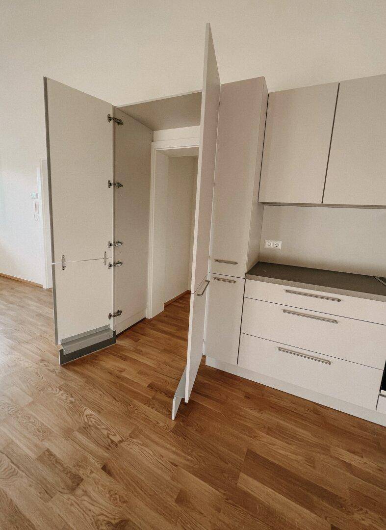 Detailansicht der modernen Einbauküche mit geöffneten Schränken und Holzboden.