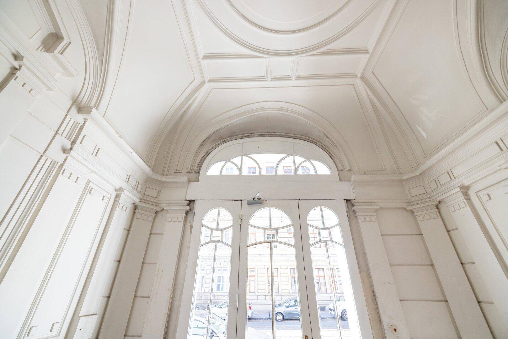 Hoher Eingangsbereich mit gewölbter Decke, Stuckverzierungen und großen Fenstertüren.