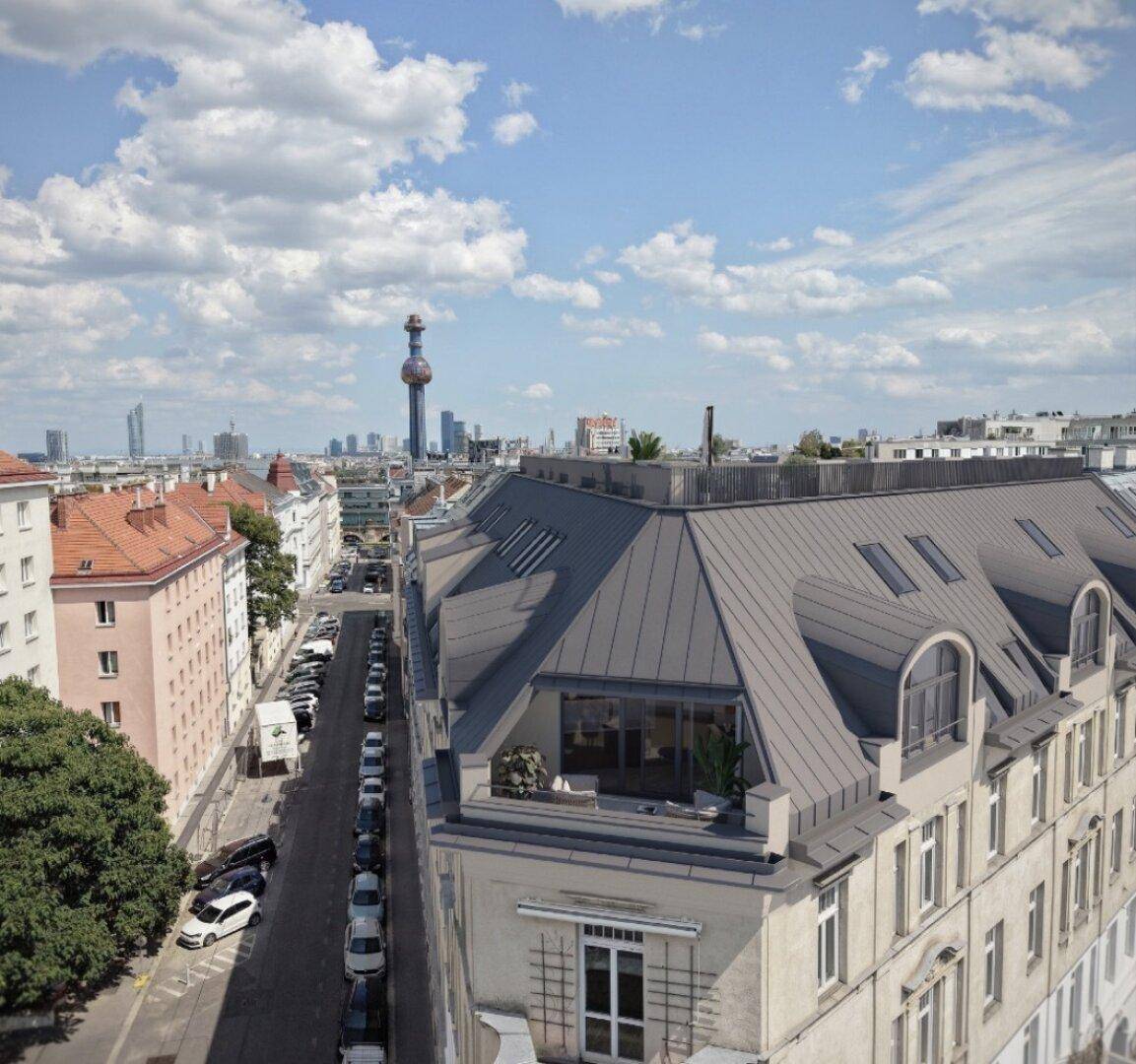 Luftaufnahme eines Gebäudes mit Dachterrassen und Blick auf die Stadtlandschaft mit Fernsehturm.
