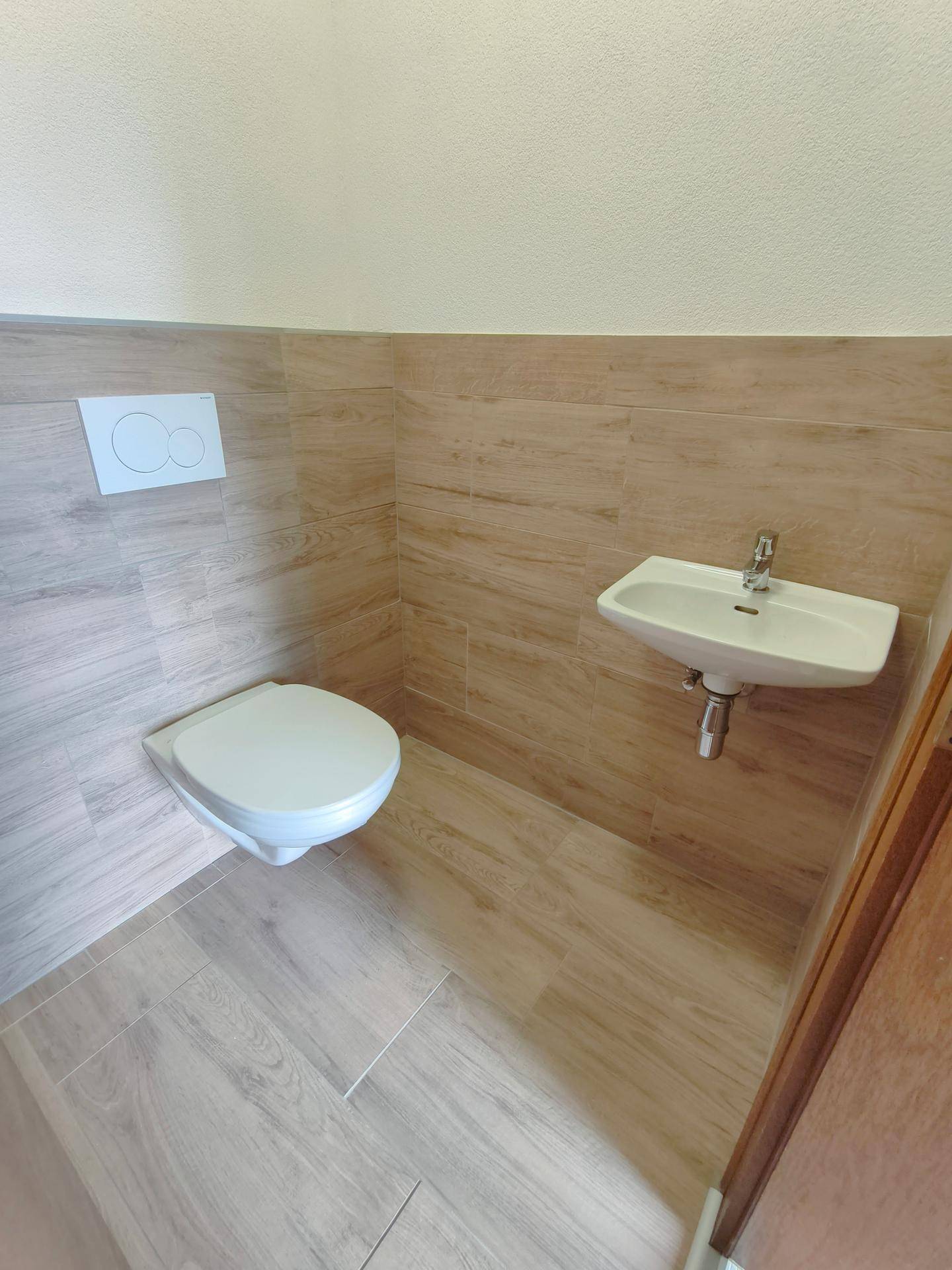Modernes Gäste-WC mit wandhängender Toilette und kleinem Waschbecken.