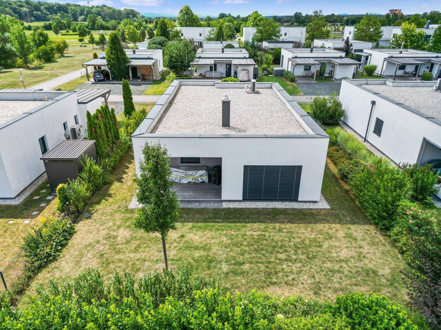 Einzelnes modernes Haus mit Flachdach, kleinem Garten und überdachter Terrasse.