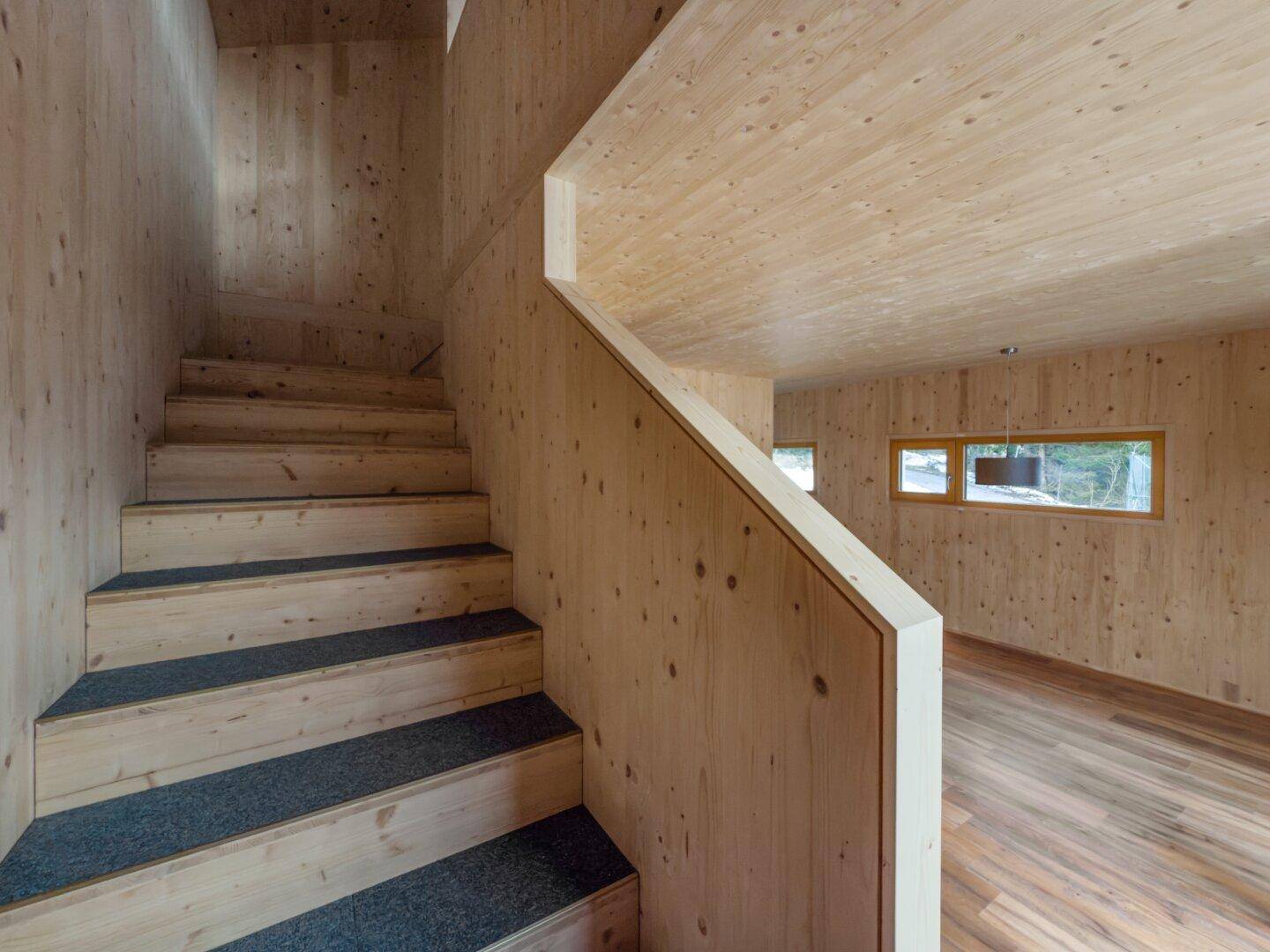 Holztreppe mit Teppichstufen, die in den oberen Bereich des Hauses führt.