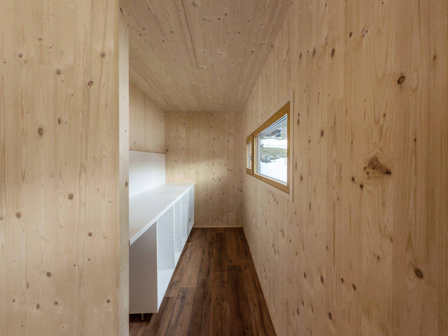Funktionaler Hauswirtschaftsraum mit Arbeitsplatte, Holzverkleidung und Fenster.