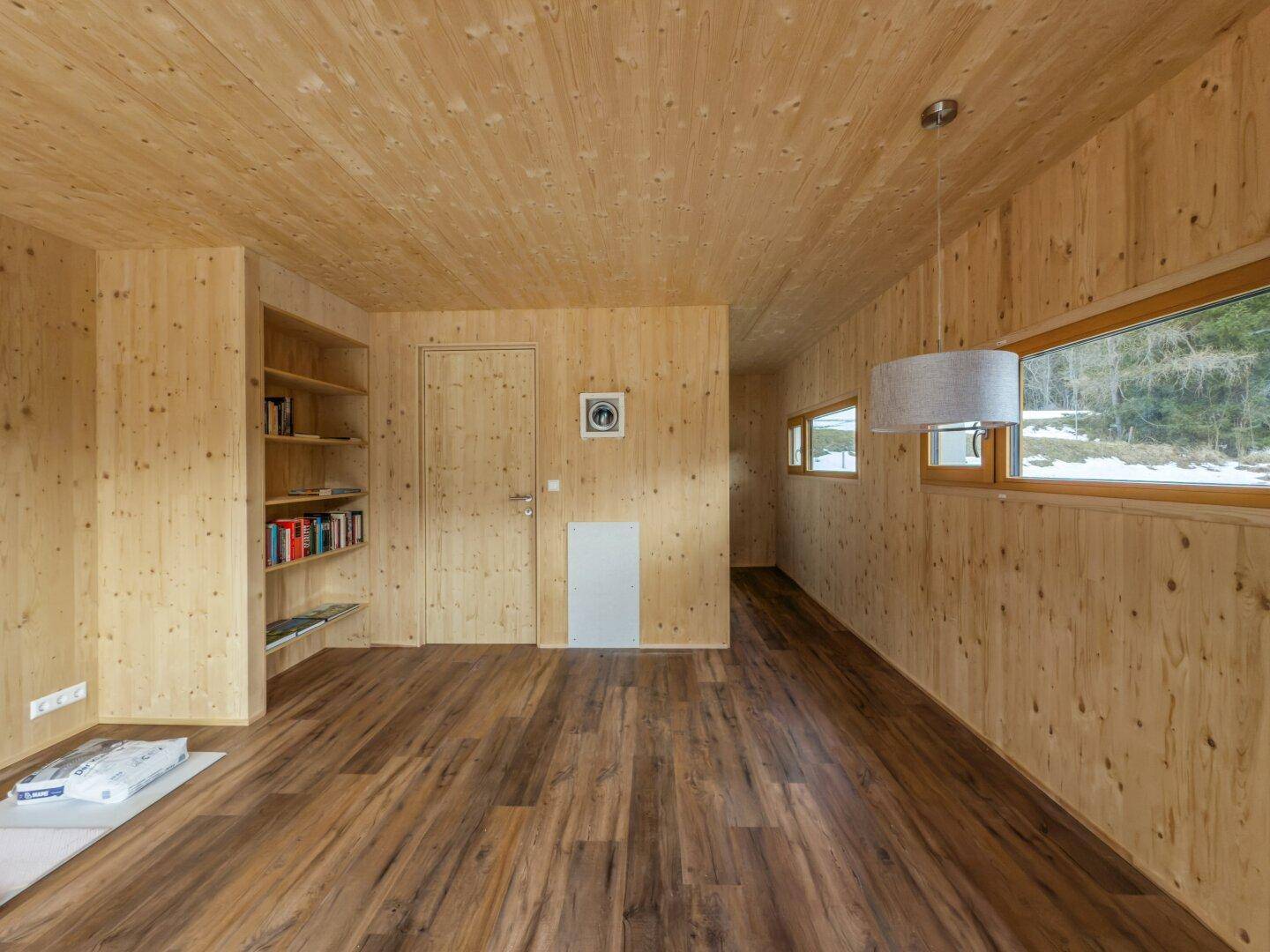Geräumiger Wohnbereich mit Holzausstattung, integrierten Regalen und viel natürlichem Licht.