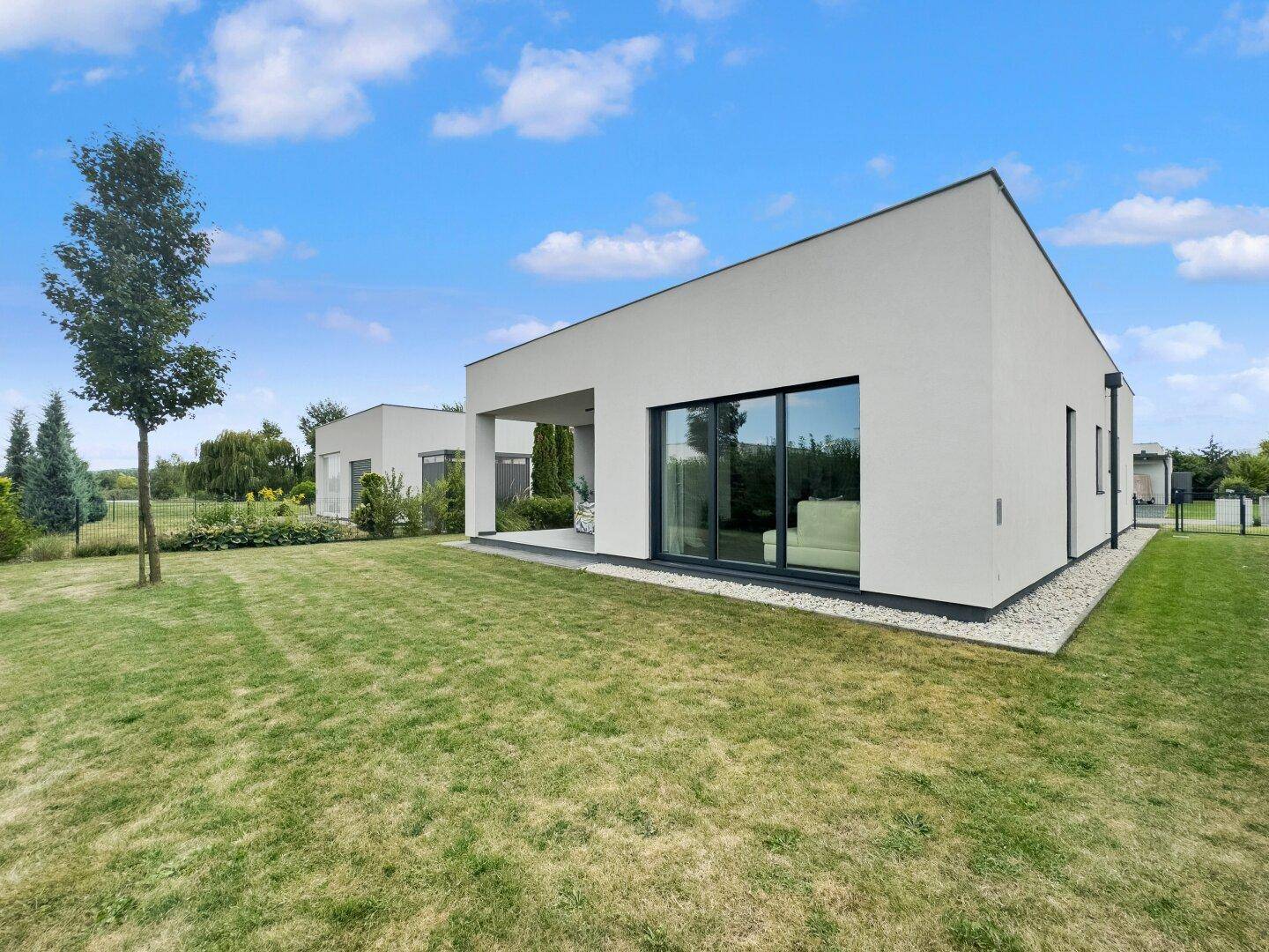 Modernes Einfamilienhaus mit großen Glasfronten und gepflegtem Rasenbereich.