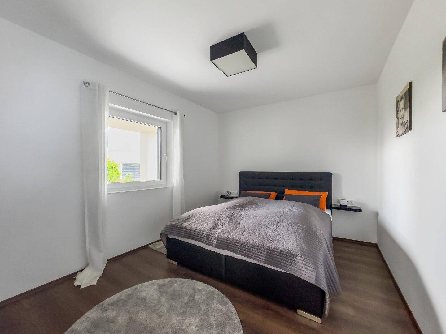 Schlafzimmer mit Doppelbett, Holzboden und einem Fenster für natürliches Licht.