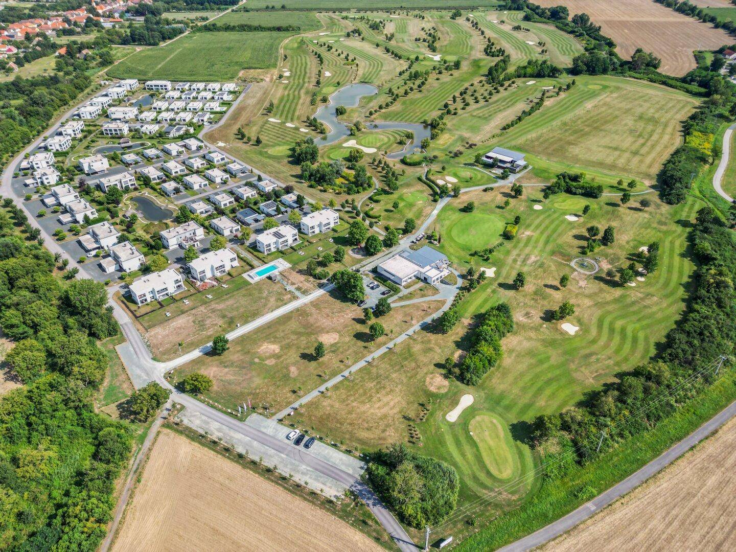 Panoramablick auf die Wohnanlage und den angrenzenden Golfplatz mit weitläufigen Grünflächen.