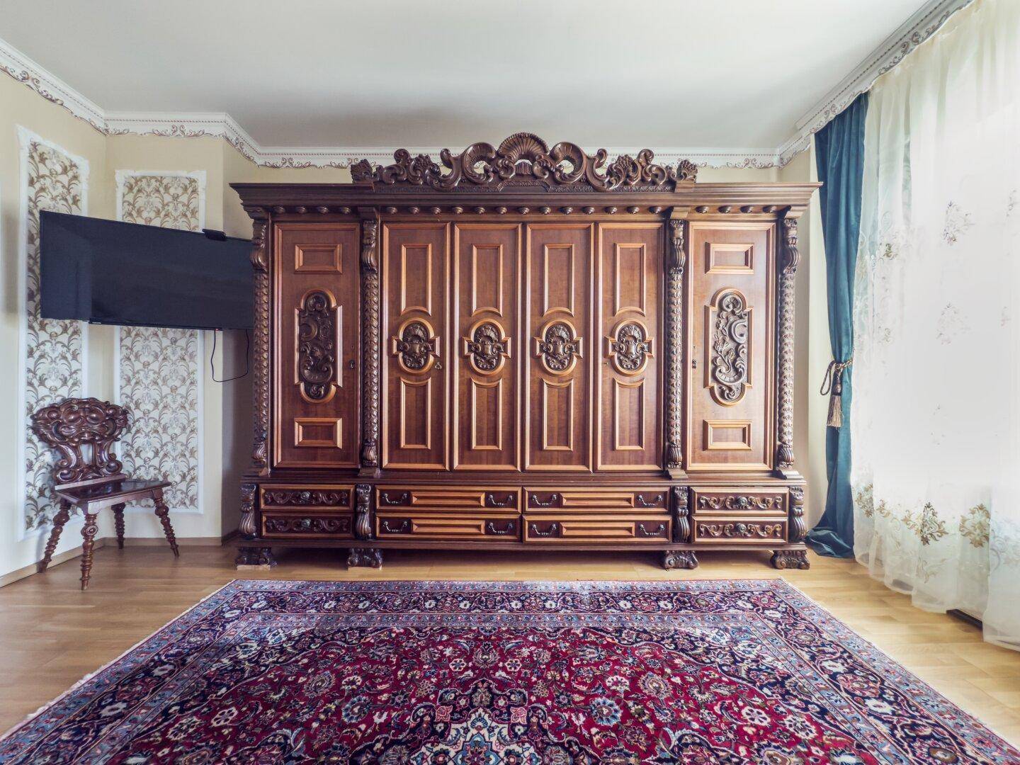 Geräumiges Schlafzimmer mit einem imposanten, reich verzierten Holzschrank und Teppichboden.