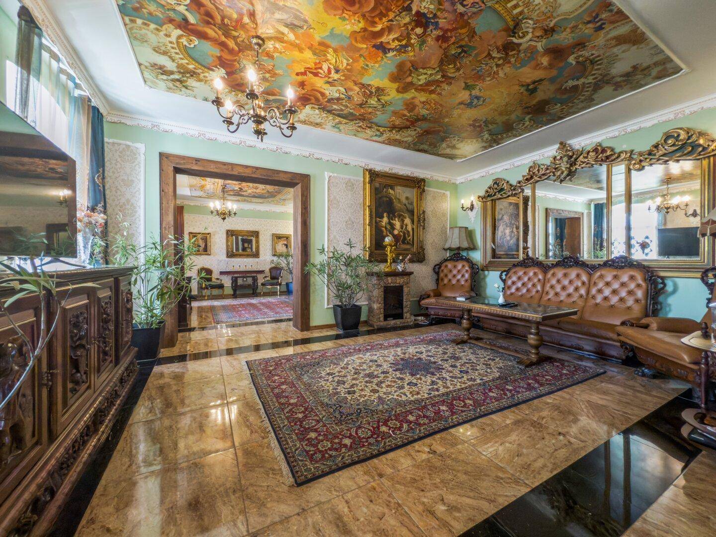 Luxuriöses Wohnzimmer mit opulenten Möbeln, bemalter Decke und glänzenden Fliesenböden.
