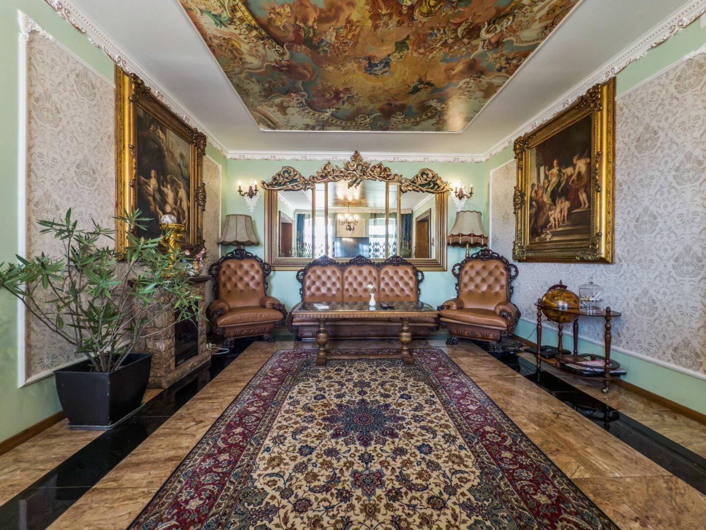 Elegantes Wohnzimmer mit Kamin, bemalter Decke, luxuriösen Möbeln und großem Spiegel.