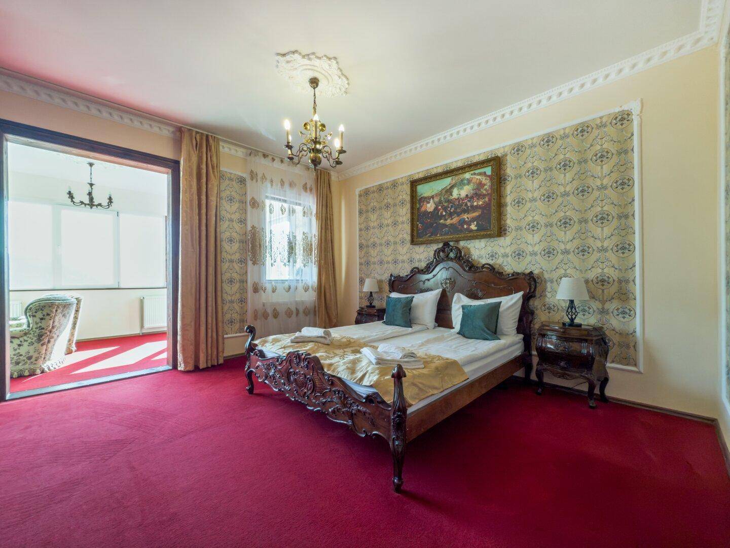 Schlafzimmer mit großem Bett, rotem Teppichboden und Zugang zu einem weiteren Raum.