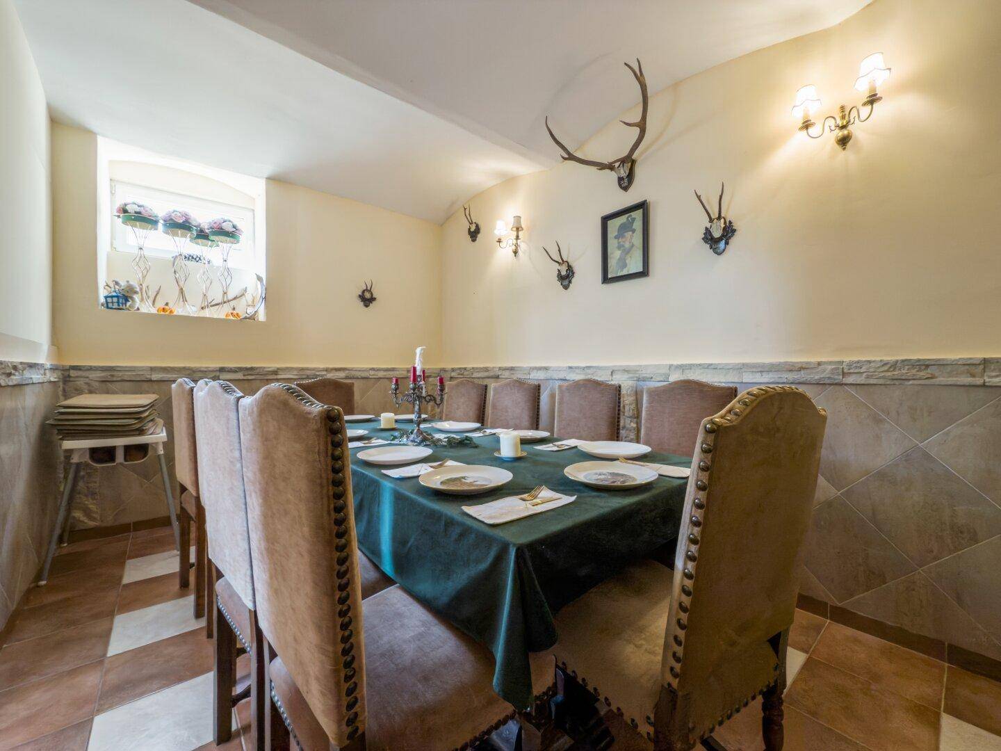 Rustikaler Speisesaal mit Jagdtrophäen an den Wänden und einem großen Esstisch für gesellige Runden.