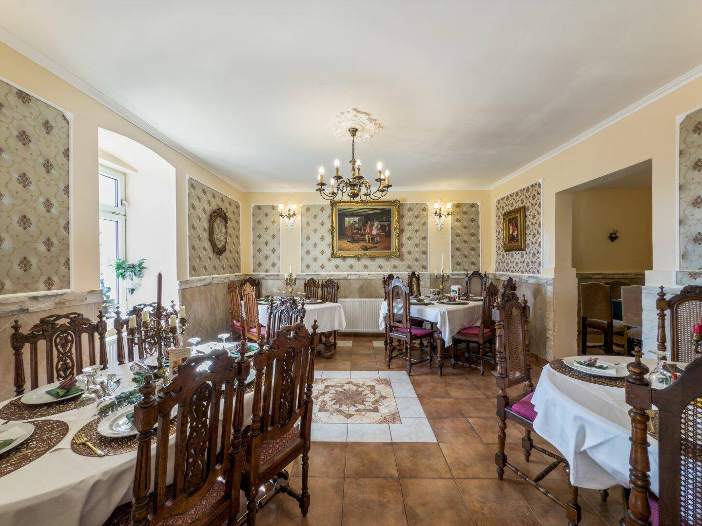 Eleganter Speisesaal mit traditionellen Holzmöbeln, gemusterten Tapeten und Kronleuchter.