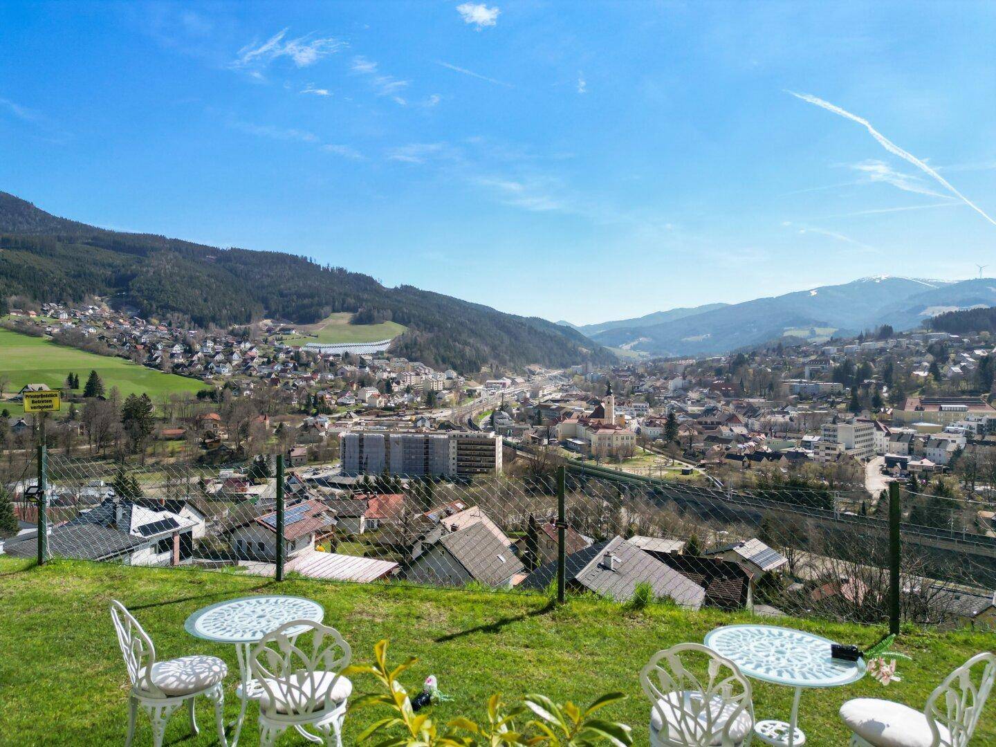 Gemütlicher Gartenbereich mit Sitzgelegenheiten und einem weiten Blick über die Stadt und die umliegenden Berge.