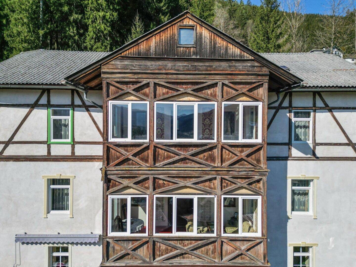 Detailansicht der traditionellen Holzfassade mit vielen Fenstern und einem kleinen Dachfenster.