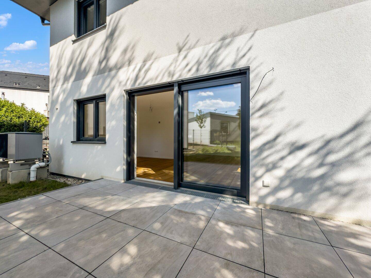 Detailansicht der gefliesten Terrasse mit großer Schiebetür zum Innenbereich des Hauses.