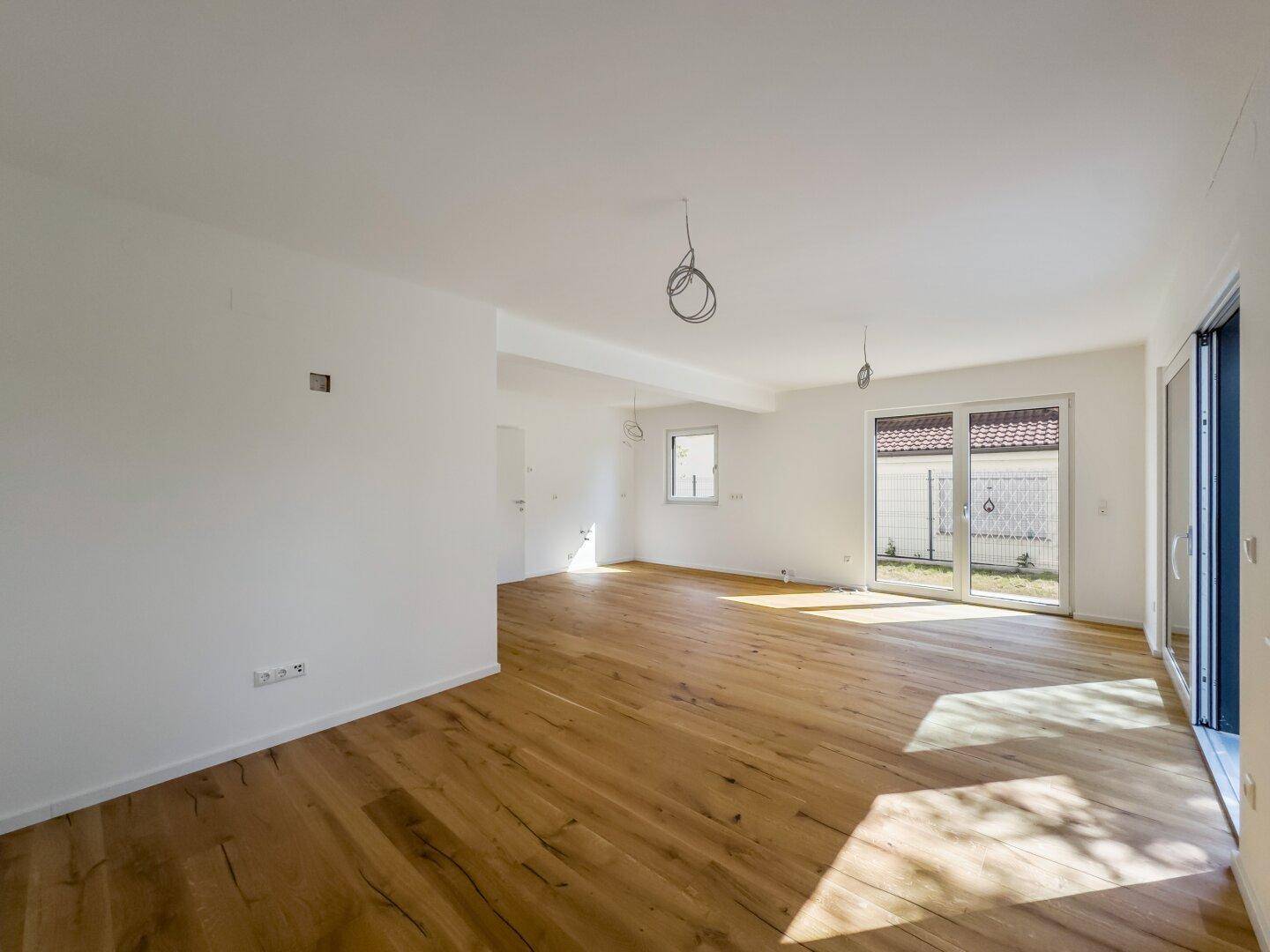 Helles, unmöbliertes Zimmer mit Holzboden und Zugang zur Terrasse, ideal für offenes Wohnen.