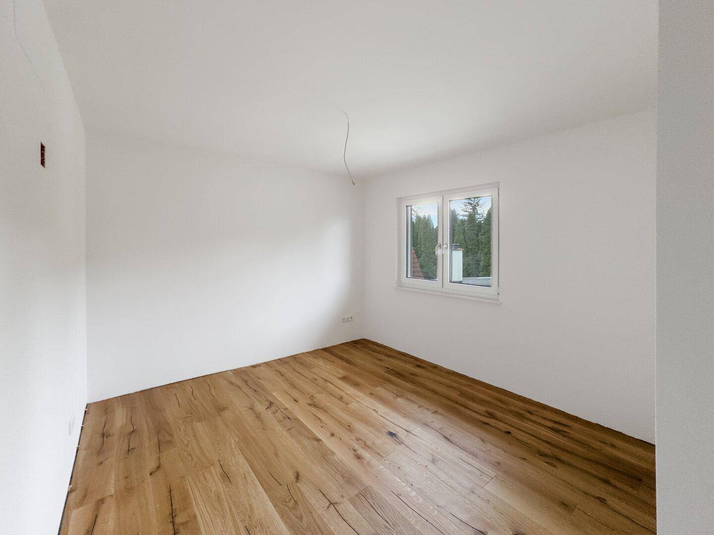 Geräumiges Schlafzimmer mit Holzboden und Fenster, das viel Tageslicht hereinlässt und eine angenehme Atmosphäre schafft.