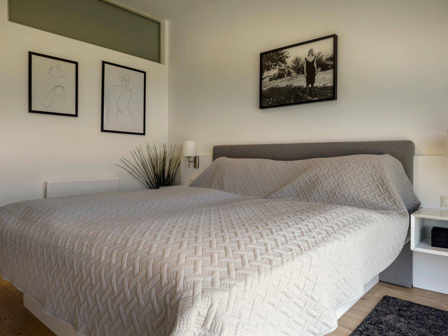 Helles Schlafzimmer mit großem Doppelbett und minimalistischer Einrichtung.