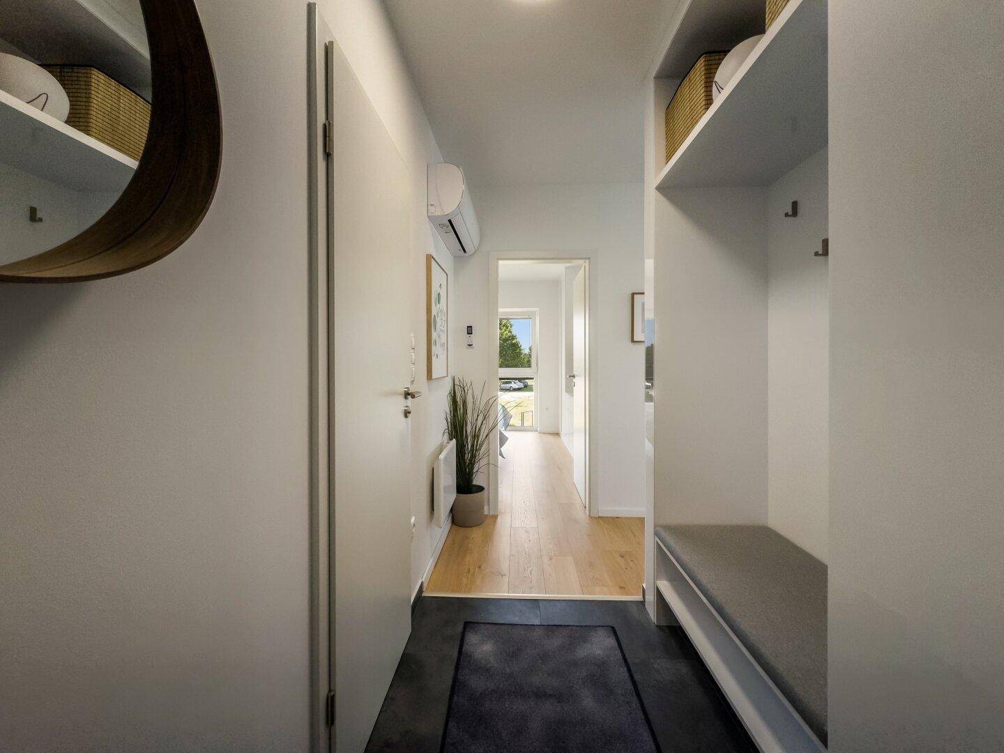 Moderner Flur mit Garderobe, Spiegel und Blick in den Wohnbereich.