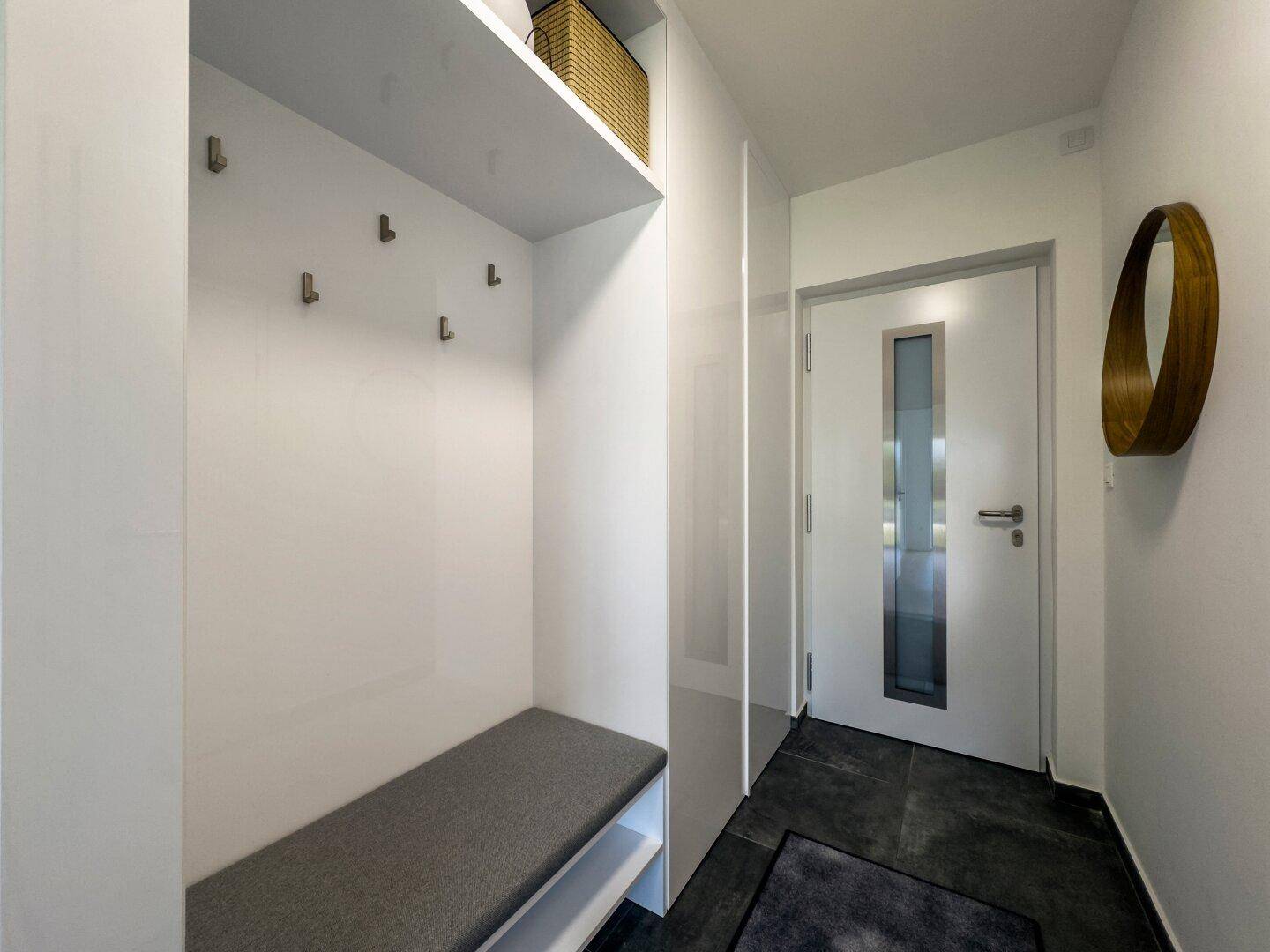 Eingangsbereich mit integrierter Sitzbank und Ablageflächen für Kleidung und Schuhe.