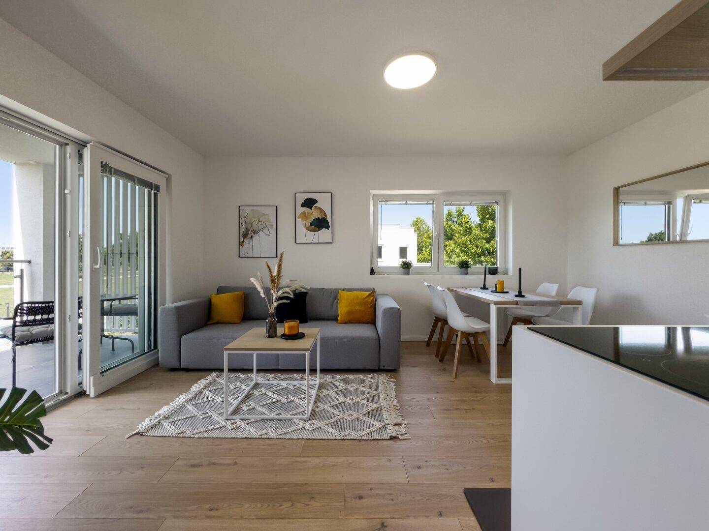 Gemütlicher Wohnbereich mit Esstisch, Sofa und großen Fenstern zum Außenbereich.