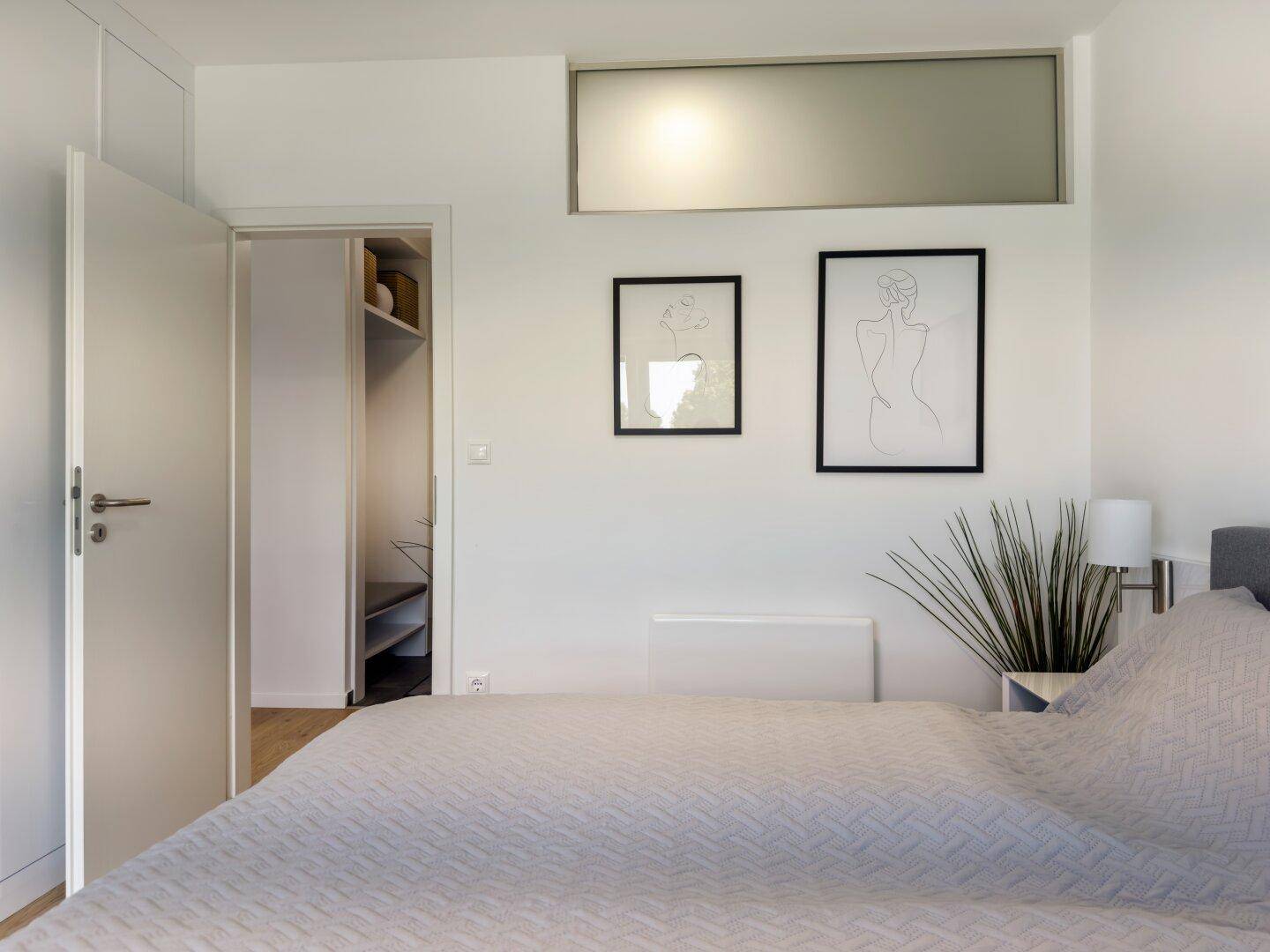 Schlafzimmer mit Zugang zu einem begehbaren Kleiderschrank und moderner Kunst.