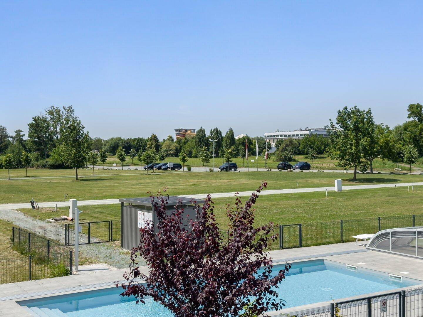 Weitläufiger Blick vom Balkon über den Pool und die grüne Landschaft.
