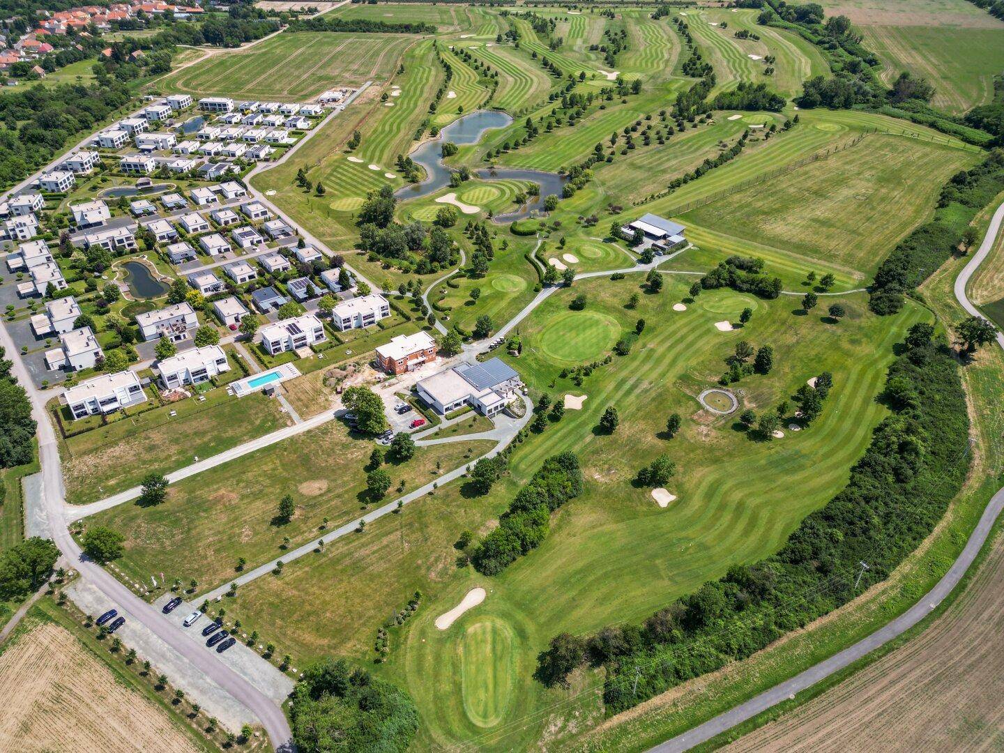 Luftaufnahme der Wohnanlage und des weitläufigen Golfplatzes mit Grünflächen.
