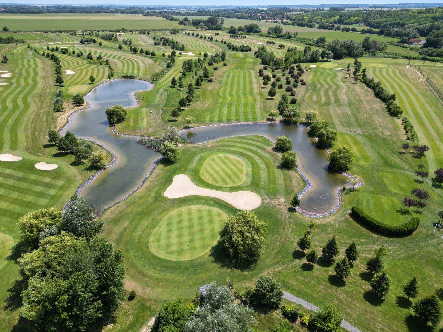 Detailreiche Luftaufnahme des Golfplatzes mit Wasserhindernissen und gepflegten Grüns.