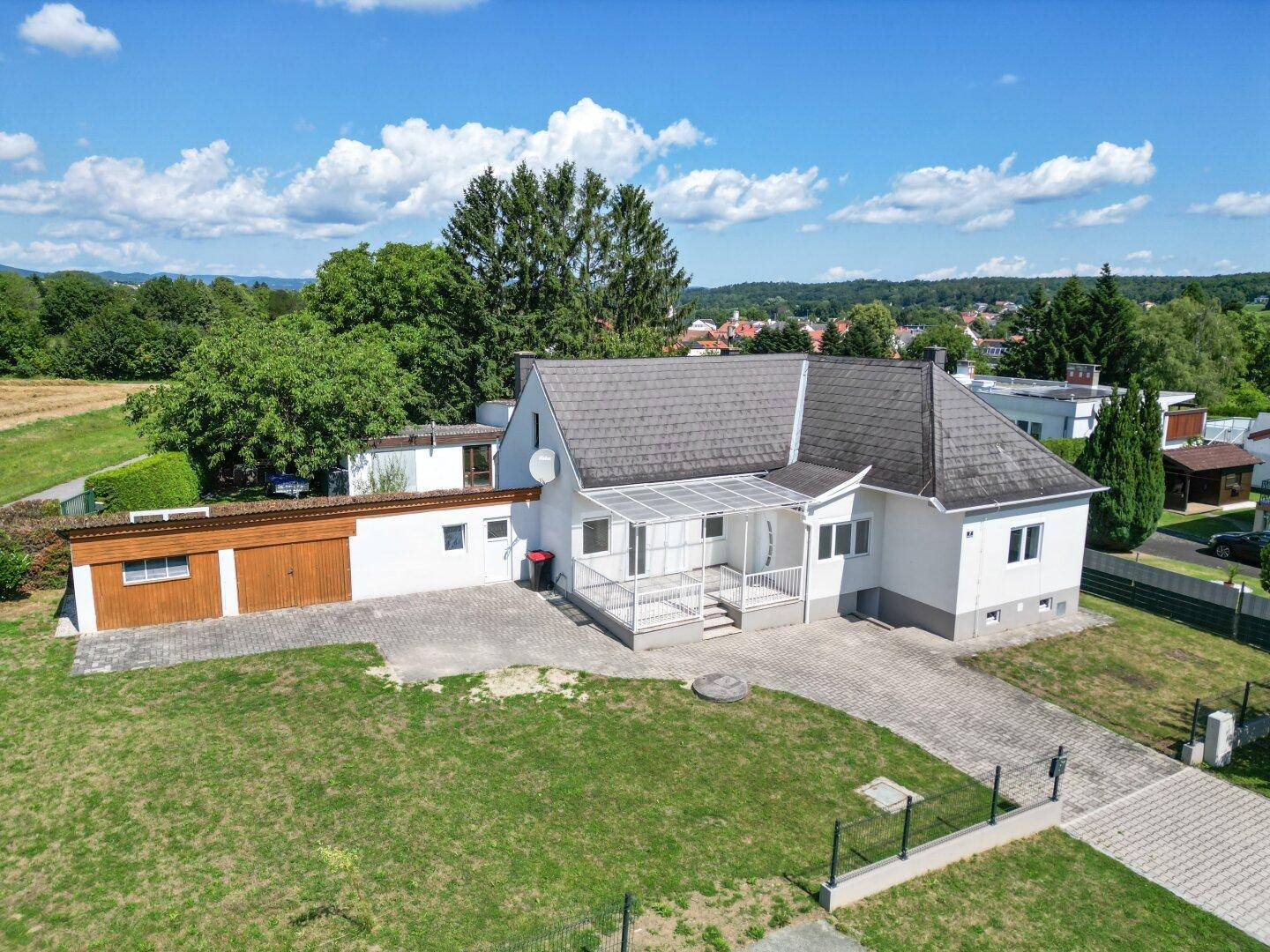 Freistehendes Haus mit Satteldach, Garage und großem Garten in ländlicher Umgebung.